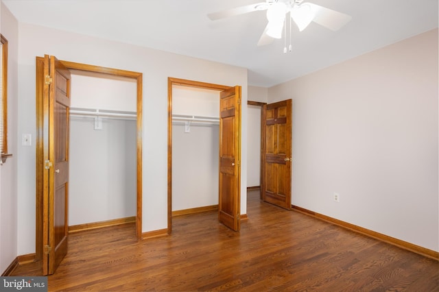 unfurnished bedroom featuring baseboards, two closets, and wood finished floors