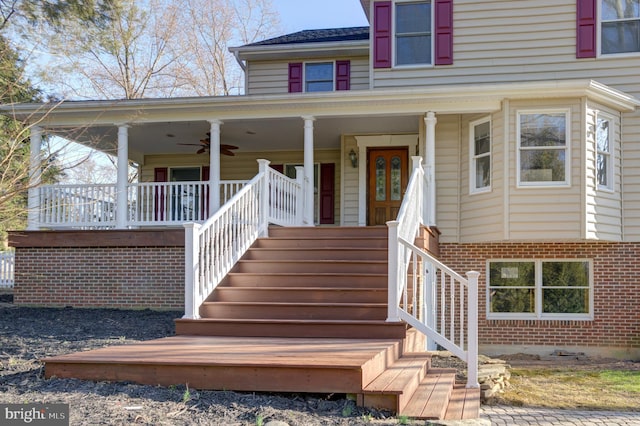 entrance to property featuring brick siding, covered porch, and a ceiling fan