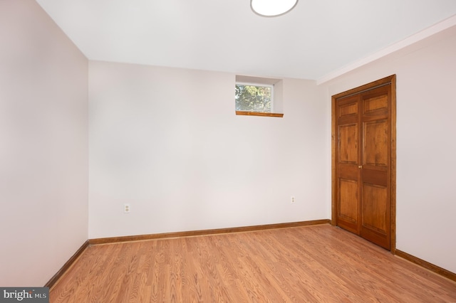 spare room with baseboards and light wood-style floors