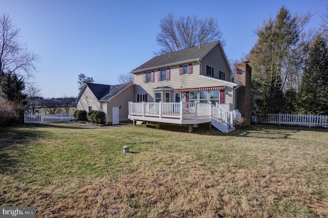 rear view of property featuring a chimney, fence, a lawn, and a wooden deck