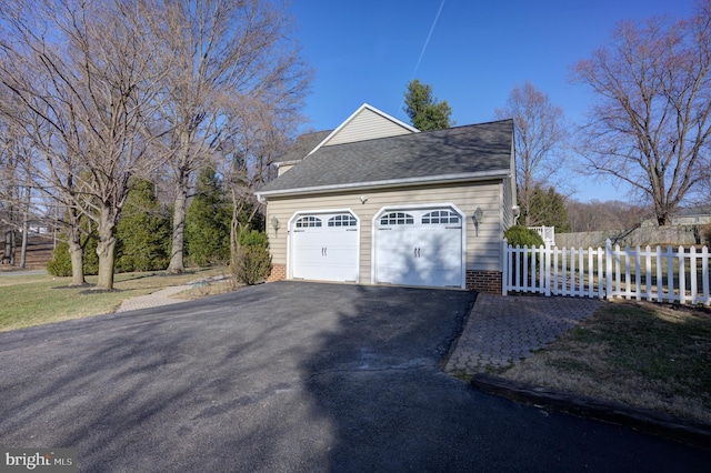 garage featuring driveway and fence