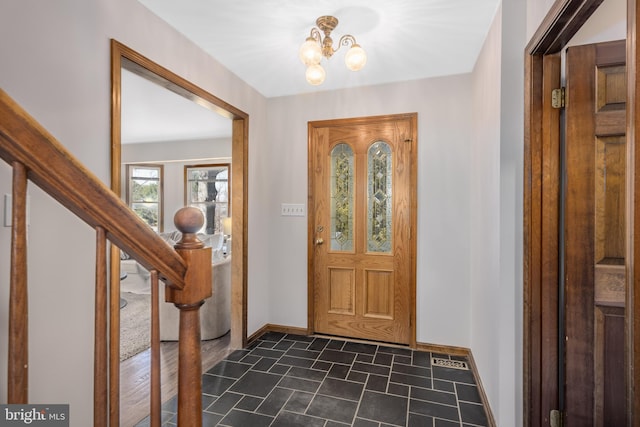 foyer with stairs, a notable chandelier, and baseboards