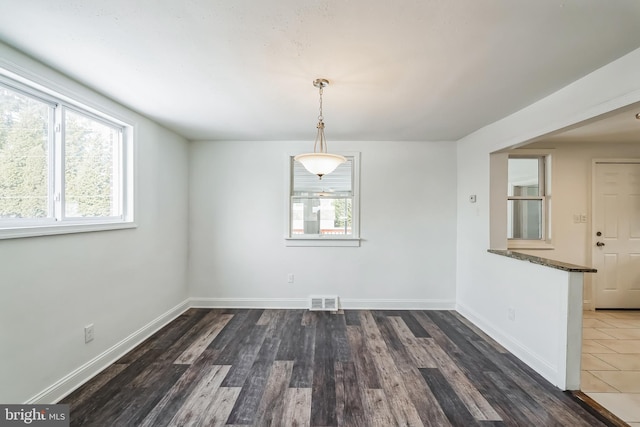 unfurnished dining area with dark wood-type flooring