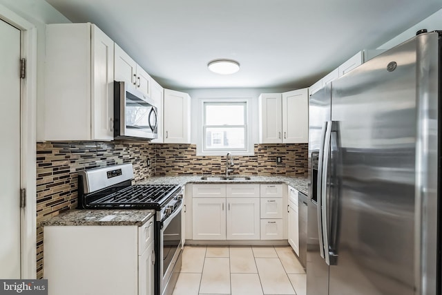 kitchen featuring white cabinets, stainless steel appliances, decorative backsplash, sink, and light stone counters