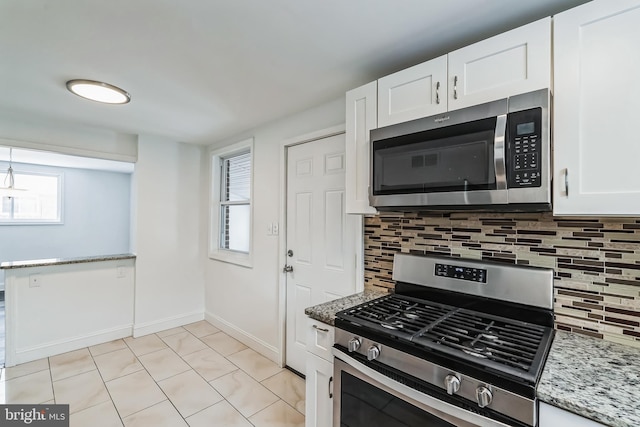 kitchen with white cabinets, decorative backsplash, light stone countertops, and appliances with stainless steel finishes