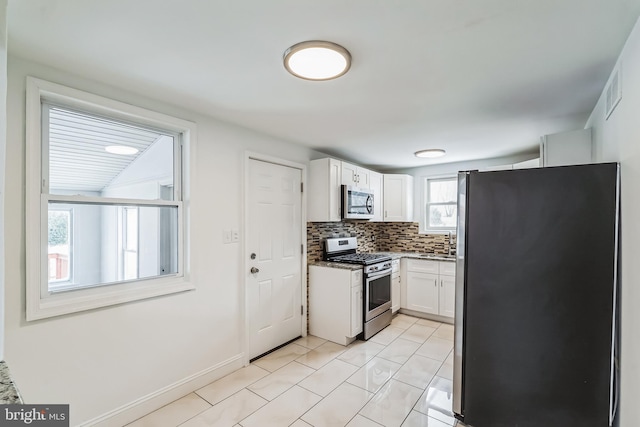 kitchen featuring light tile patterned floors, backsplash, white cabinetry, and appliances with stainless steel finishes