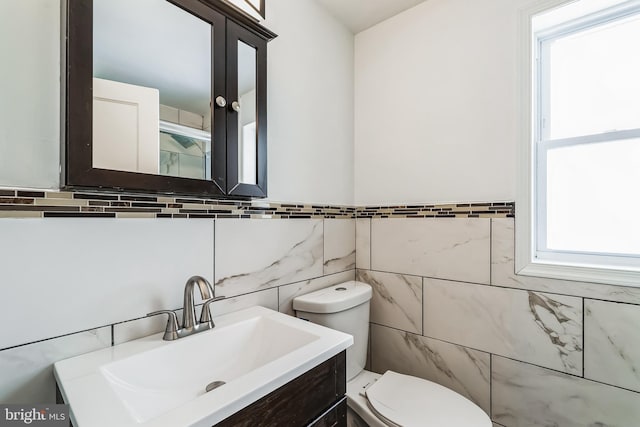 bathroom with vanity, toilet, tile walls, and plenty of natural light