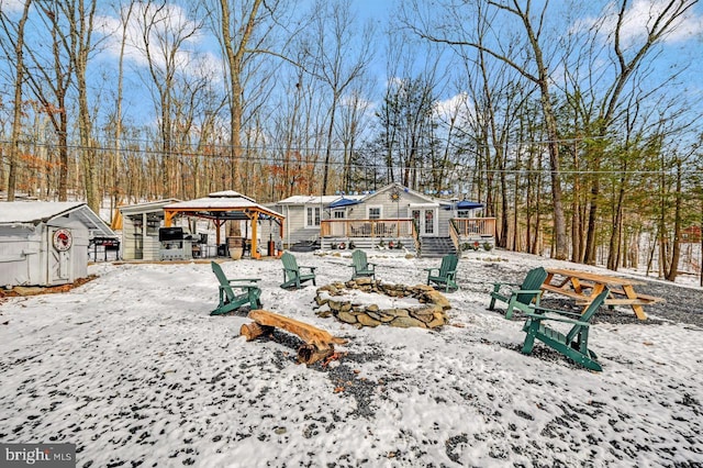 yard layered in snow with a gazebo, a fire pit, and a deck