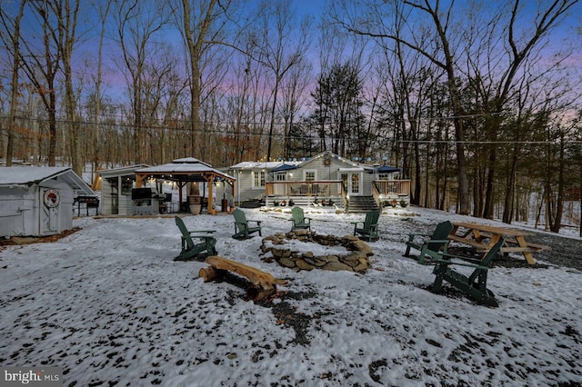 yard covered in snow with a gazebo, a fire pit, and a deck