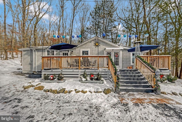 snow covered rear of property with a deck