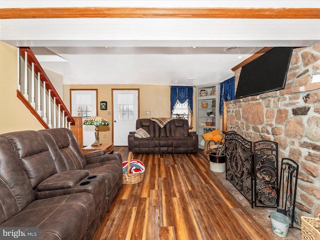 living room featuring dark hardwood / wood-style floors, built in features, and a fireplace