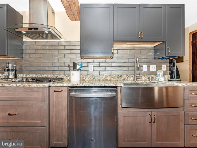 kitchen featuring wall chimney range hood, sink, backsplash, stainless steel appliances, and light stone counters