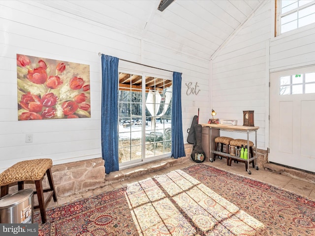 entryway featuring wooden walls and high vaulted ceiling