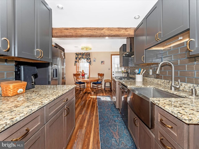 kitchen with wall chimney range hood, dark wood-type flooring, backsplash, beam ceiling, and light stone countertops