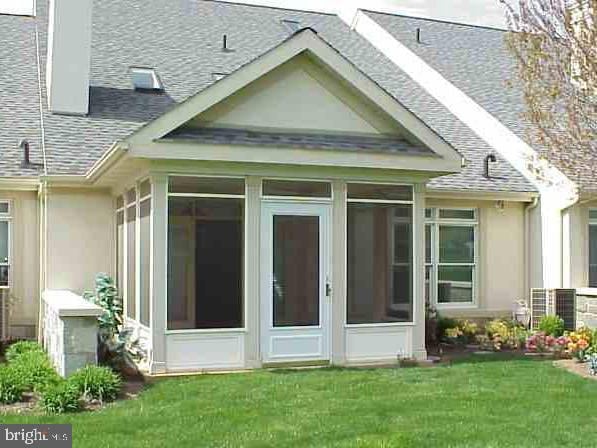 view of side of property with a lawn and a sunroom