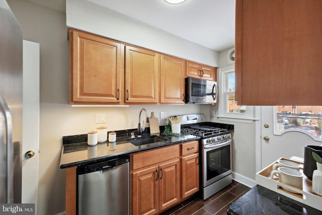 kitchen featuring appliances with stainless steel finishes, dark stone counters, and sink