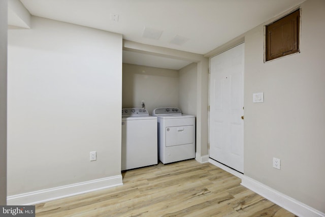 laundry area with washer and dryer and light hardwood / wood-style floors