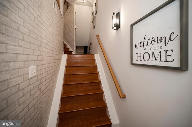 staircase featuring brick wall