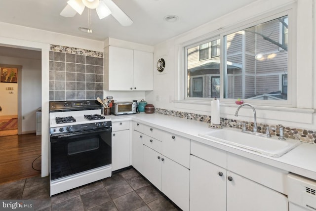 kitchen with sink, white cabinetry, dishwashing machine, ceiling fan, and gas range oven