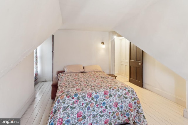 bedroom with vaulted ceiling and light wood-type flooring