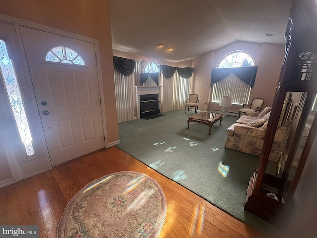 entrance foyer featuring lofted ceiling, a textured ceiling, and hardwood / wood-style flooring