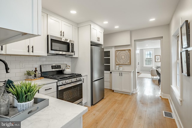 kitchen with light stone countertops, white cabinets, and appliances with stainless steel finishes