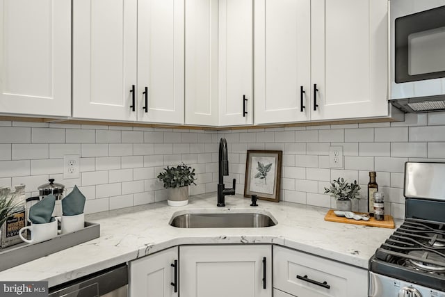 kitchen featuring appliances with stainless steel finishes, tasteful backsplash, white cabinetry, and sink