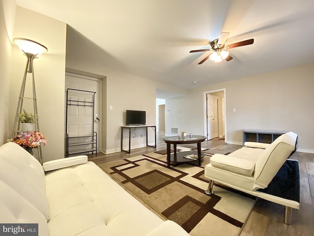 living room with ceiling fan and dark wood-type flooring