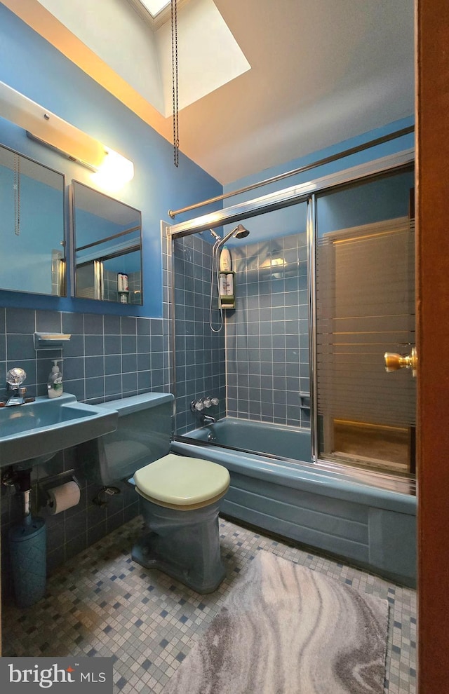 bathroom featuring tile patterned floors, toilet, tiled shower / bath combo, and tile walls