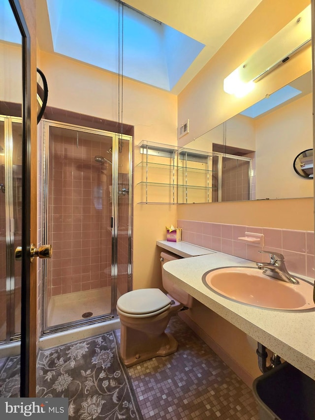 bathroom with sink, a shower with door, decorative backsplash, tile patterned floors, and toilet