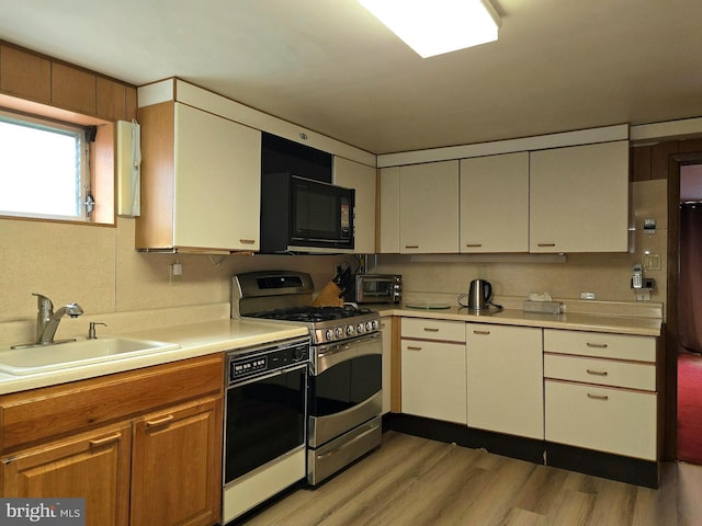 kitchen featuring sink, light hardwood / wood-style flooring, and black appliances