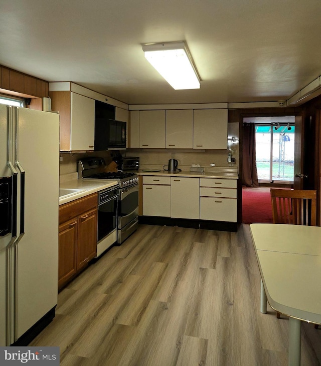 kitchen with light hardwood / wood-style flooring, black appliances, and cream cabinetry