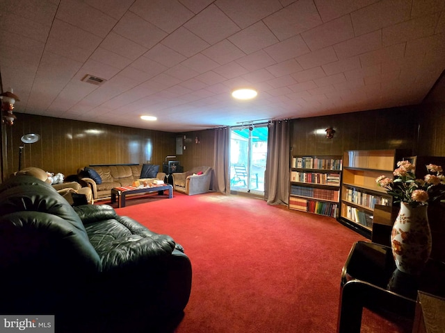 carpeted living room featuring wood walls