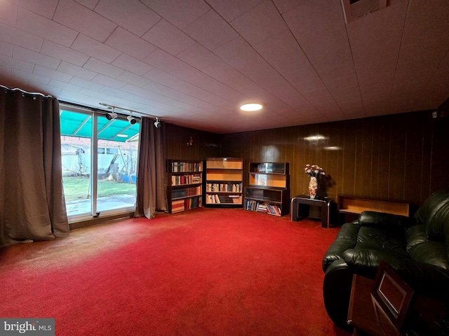 sitting room featuring carpet floors and wooden walls