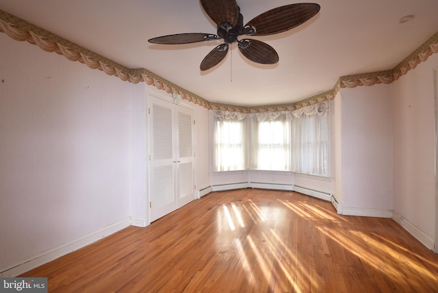 spare room featuring hardwood / wood-style floors, ceiling fan, and a baseboard heating unit