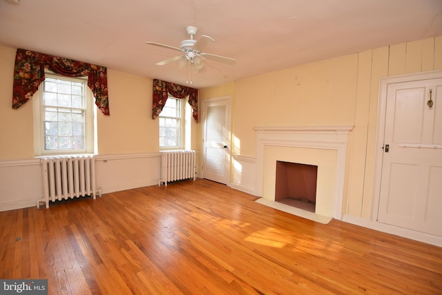 unfurnished living room featuring radiator, ceiling fan, and wood-type flooring