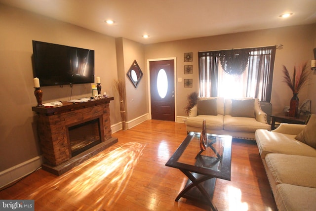 living room with a stone fireplace and light hardwood / wood-style flooring