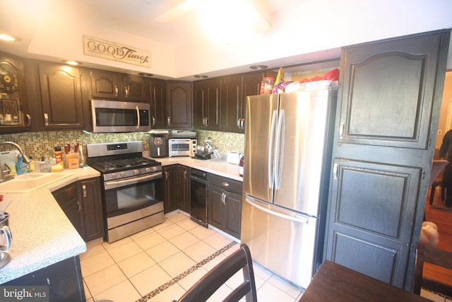 kitchen with sink, decorative backsplash, light tile patterned floors, appliances with stainless steel finishes, and dark brown cabinetry