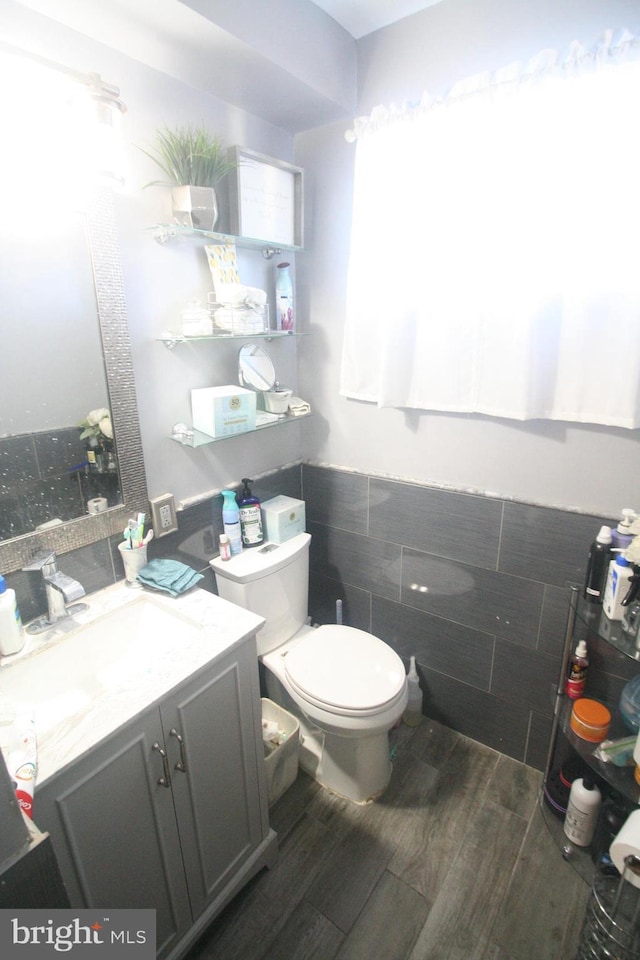 bathroom with vanity, tile walls, and toilet