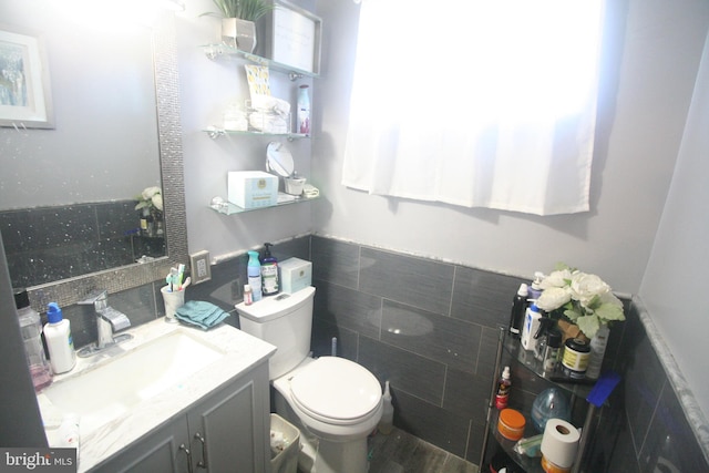 bathroom featuring vanity, tile walls, and toilet