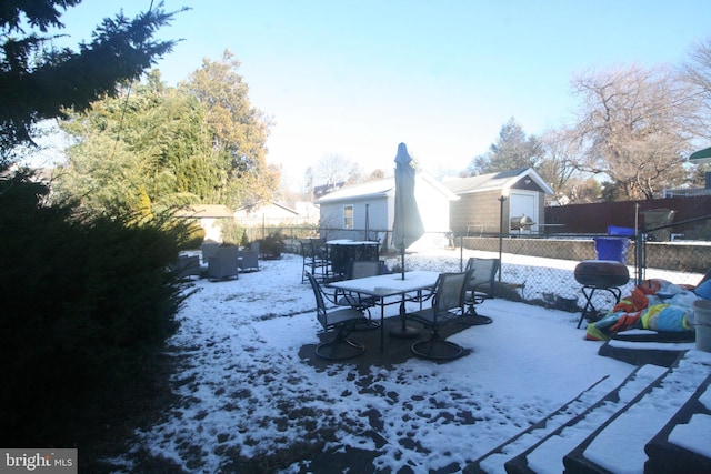 snowy yard with a garage and an outbuilding