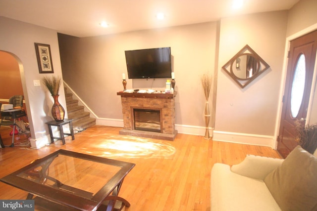 living room featuring a stone fireplace and hardwood / wood-style flooring