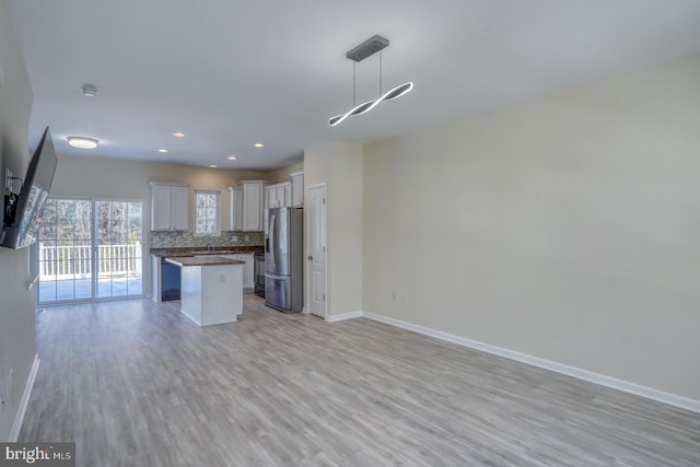 kitchen with a kitchen island, pendant lighting, tasteful backsplash, white cabinetry, and stainless steel fridge with ice dispenser