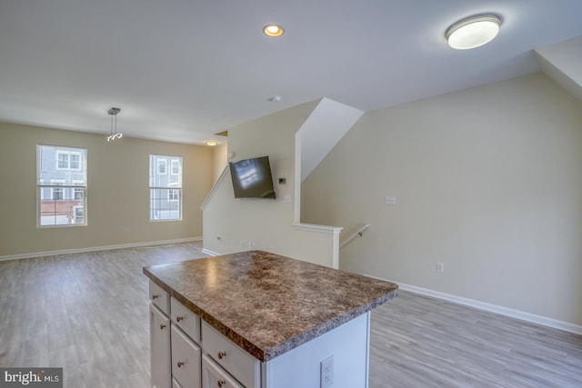 kitchen featuring white cabinetry, a center island, light hardwood / wood-style floors, and hanging light fixtures