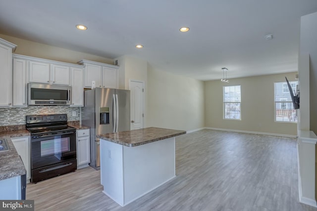 kitchen featuring white cabinetry, stainless steel appliances, a center island, and decorative backsplash