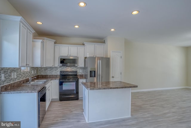 kitchen with sink, white cabinets, backsplash, a center island, and black appliances