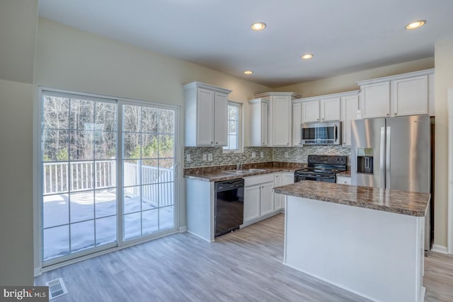 kitchen with sink, white cabinetry, light hardwood / wood-style floors, decorative backsplash, and black appliances