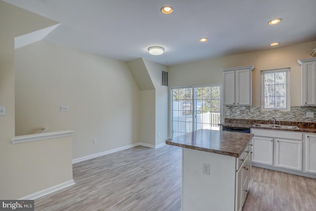 kitchen with a kitchen island, tasteful backsplash, sink, white cabinets, and light hardwood / wood-style floors