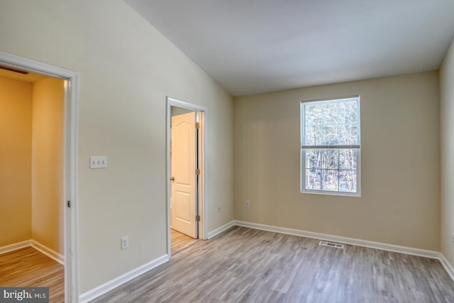 unfurnished bedroom with vaulted ceiling and light hardwood / wood-style flooring