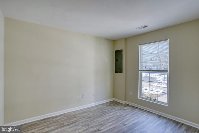 empty room featuring electric panel and light hardwood / wood-style flooring